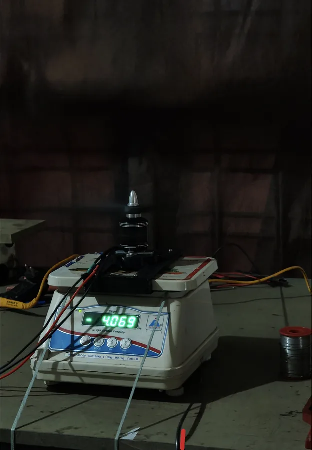 A motor and propeller mounted on a bench scale during thrust testing, the display reading 4069