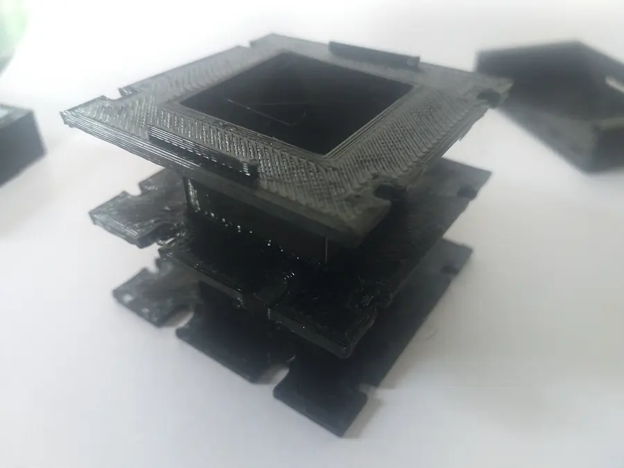 Black 3D printed bobbin, printed in two halves, showing the winding barrel and the notched flanges