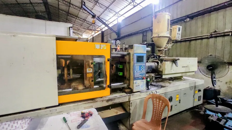 Injection moulding machine on the supplier factory floor, with hopper, clamping unit and control panel